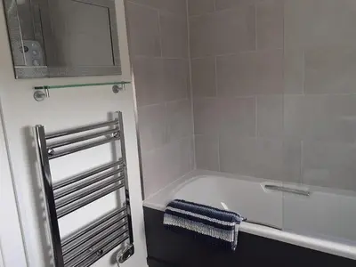 a bathroom with a bath tub and a sink at Barnacle in Mainsriddle