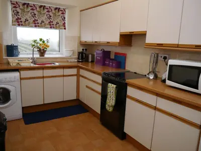 a kitchen with white cabinets and a black stove top oven at Shelduck Cottage in Mainsriddle