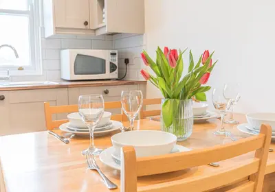 a dining room table with wine glasses and a vase of flowers at 7 Greta Grove House in Keswick