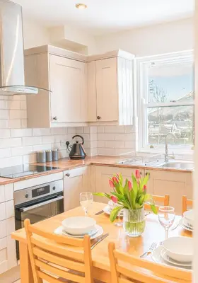 a kitchen with a wooden table with chairs and a sink at 7 Greta Grove House in Keswick