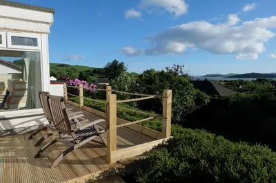 a wooden deck with a chair on a house at Tir Nan Og in Rockcliffe