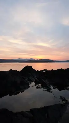 a sunset over a body of water with rocks at Tir Nan Og in Rockcliffe