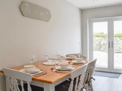a dining room with a wooden table with white chairs at Crofthouse - Uk43405 in Wigtown