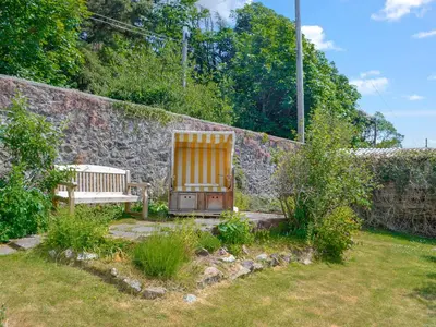 a garden with a bench and a stone wall at Mossdale in Rockcliffe
