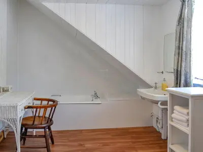 a white bathroom with a sink and a chair at Mossdale in Rockcliffe