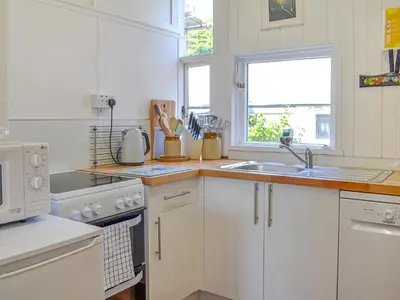 a kitchen with white cabinets and a sink and a window at Mossdale in Rockcliffe
