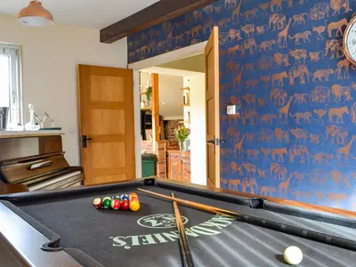 a pool table in a living room with a wall at The Coach House in Blencogo