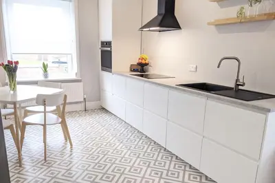 a kitchen with white cabinets and a table and a sink at Townhouse Apartment Carlisle in Carlisle