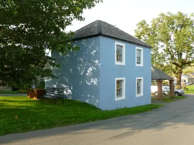 a blue house with a bench in the grass at The Coach House, Hesket Newmarket in Hesket Newmarket