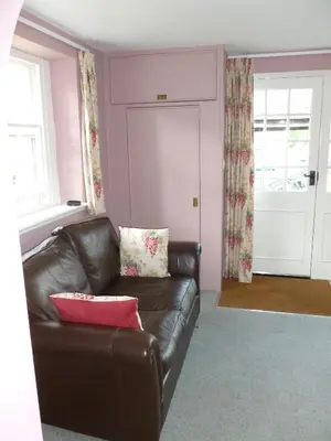 a living room with a leather couch and a window at The Coach House, Hesket Newmarket in Hesket Newmarket