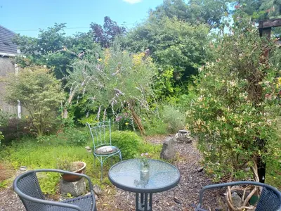 a table and two chairs in a garden at BARHOLM CROFT Holiday Cottage in Creetown