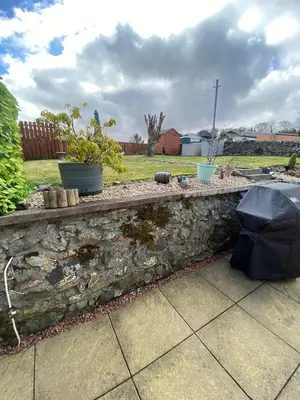 a stone retaining wall with plants and an umbrella at Minton cottage in Leadhills