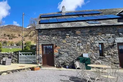 a stone house with solar panels on the roof at The Hayloft. Entire Barn Conversion near Keswick in Applethwaite