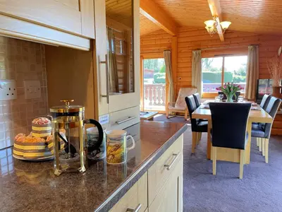 a kitchen with a counter top with a dining table at Beautiful Norwegian Lodge in Kippford with Garden - Pass the Keys in Dalbeattie
