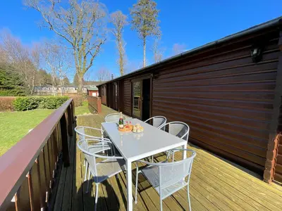 a white table and chairs on a deck at Beautiful Norwegian Lodge in Kippford with Garden - Pass the Keys in Dalbeattie