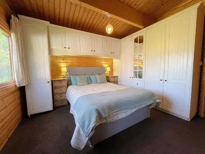 a bedroom with a large bed with white cabinets at Beautiful Norwegian Lodge in Kippford with Garden - Pass the Keys in Dalbeattie