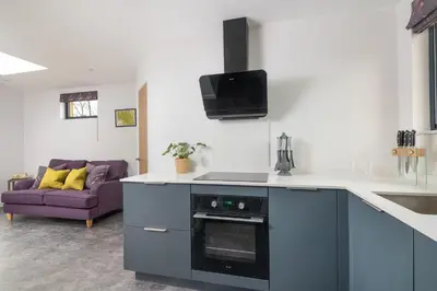 a kitchen with a stove top oven next to a couch at Snowdrop, Penruddock an Eco and dog friendly lodge with hot tub, 10 minutes to Lake Ullswater in Penruddock