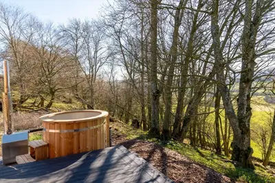 a wooden hot tub sitting on the side of a yard with trees at Snowdrop, Penruddock an Eco and dog friendly lodge with hot tub, 10 minutes to Lake Ullswater in Penruddock