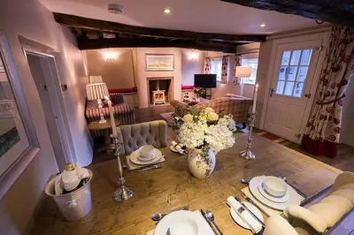 a living room with a table and flowers in a room at Porch Cottage, a luxurious characterful cottage within walking distance of Keswick town centre in Keswick