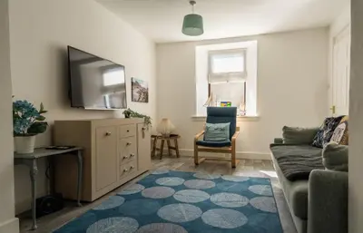 a living room with a couch and a tv at The Portpatrick Pad - A cosy 3 bed cottage, w. sea views & garden office in Portpatrick