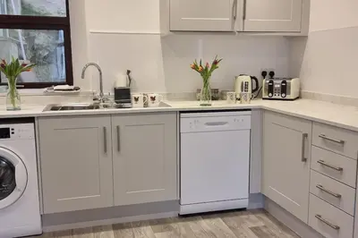a white kitchen with a sink and a dishwasher at The Portpatrick Pad - A cosy 3 bed cottage, w. sea views & garden office in Portpatrick