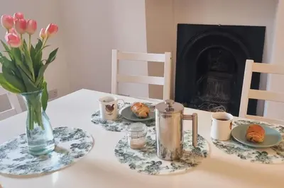 a table with plates of food and a vase of flowers at The Portpatrick Pad - A cosy 3 bed cottage, w. sea views & garden office in Portpatrick