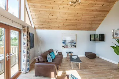 a living room with a couch and a wooden ceiling at Kestrel Lodge 2 with Hot Tub in Newton Stewart