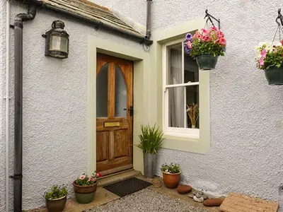 a white house with a door and potted plants at Gulls Hatch in Maryport