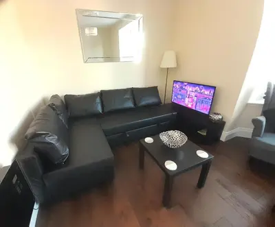 a living room with a black couch and a table at Kirkcudbright Holiday Apartments - Apartment C in Kirkcudbright