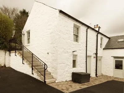 a white brick building with a staircase on it at Skerrow in New Galloway