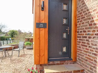 a black door with a table and chairs next to a brick building at The Flat in Carlisle