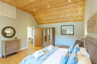 a bedroom with a bed and a wooden ceiling at Osprey Lodge 1 with Hot Tub in Newton Stewart