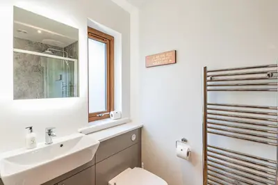 a bathroom with a sink and a toilet and a mirror at Osprey Lodge 1 with Hot Tub in Newton Stewart