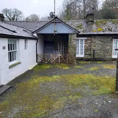 an old stone house with a yard in front of it at 1 Bridge Syke Elterwater in Ambleside
