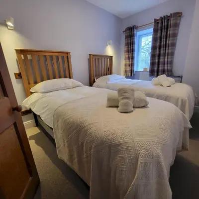 a bedroom with two beds with towels on them at 1 Bridge Syke Elterwater in Ambleside