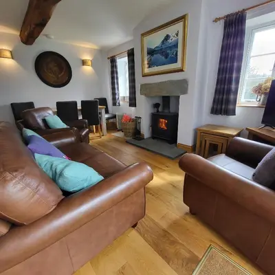 a living room with leather furniture and a fireplace at 1 Bridge Syke Elterwater in Ambleside