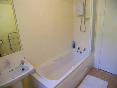 a white bathroom with a tub and a sink at Glenauld Cottage in Kirkcudbright
