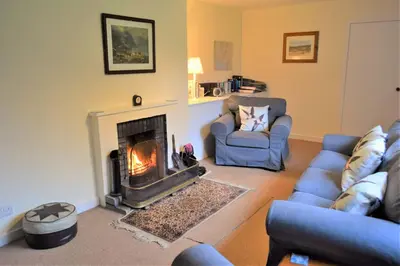 a living room with a fireplace and two couches at Glenauld Cottage in Kirkcudbright