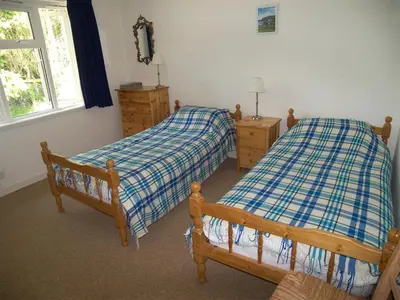 a bedroom with two beds and a window at Glenauld Cottage in Kirkcudbright