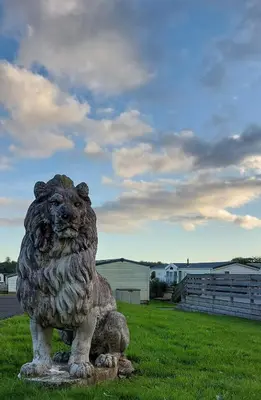 a statue of a lion sitting in the grass at Just Resort No29 in Balminnoch