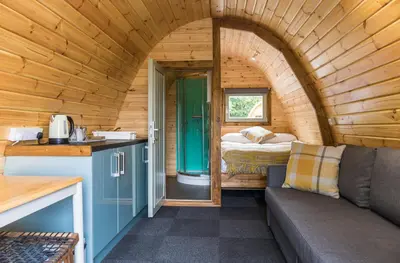 a room with a couch and a bed in a tiny house at Cosy Glamping In the Eskdale Valley - Studio Lodges and Mega Pods in Eskdale