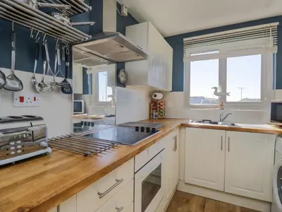 a kitchen with white cabinets and a wooden counter top at Seaspray in St Bees