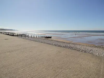 a beach with a row of benches and the ocean at Seaspray in St Bees