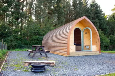 a small wooden tent with a picnic table and a grill at Glamping Pod 2 Magical Craigengillan Estate in Dalmellington