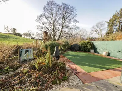 a garden with a green lawn and a fence at Millbrook Cottage in Dalbeattie