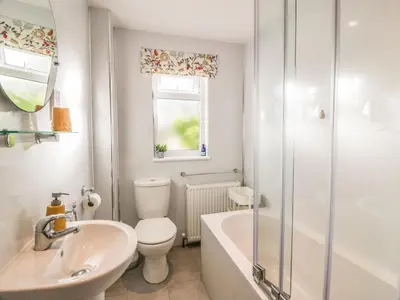 a bathroom with a toilet and a sink and a bath tub at Millbrook Cottage in Dalbeattie