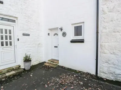 a white house with a door and a window at Millbrook Cottage in Dalbeattie