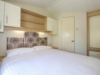 a bedroom with a large white bed with white cabinets at Swinside in Cockermouth