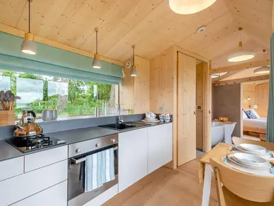 a kitchen with white cabinets and a table in a room at The Curve At Caerlaverock Estate in Glencaple