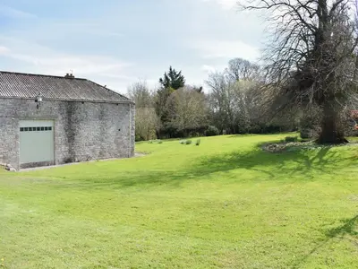 a large grassy field next to a brick building at Rushgill House in Sebergham